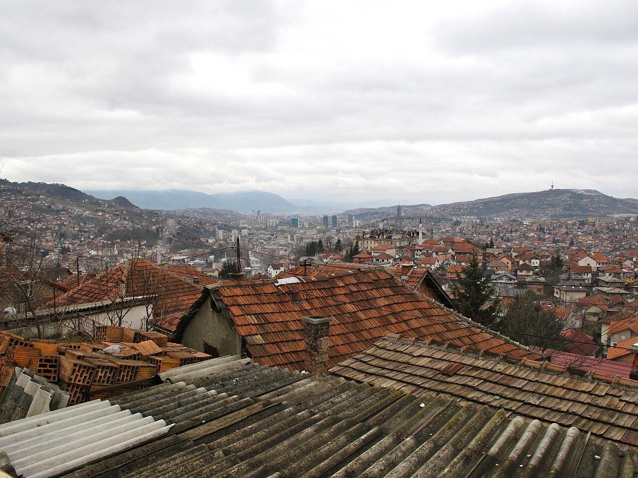 Sarajevo International Airport terminal exterior with hillside town in background